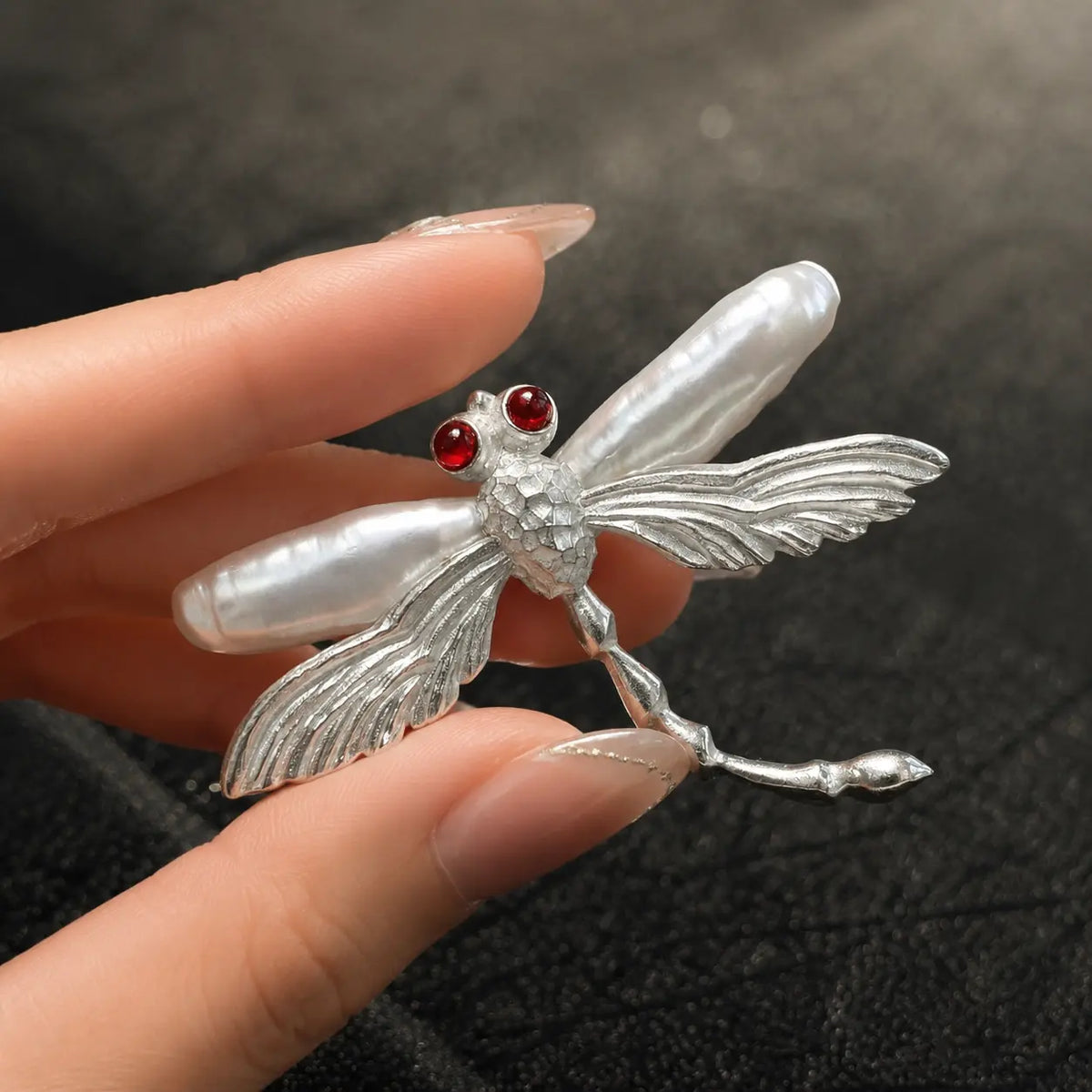 Sterling silver hovering dragonfly brooch pinned to textile — handmade jewelry detail