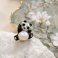 Hewren Jewelry sterling silver panda brooch pendant with black enamel details and a lustrous baroque pearl belly on white stone beside a floral dish