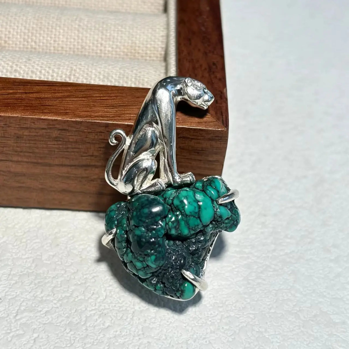 Sterling silver seated leopard brooch pinned to textile — handmade jewelry detail
