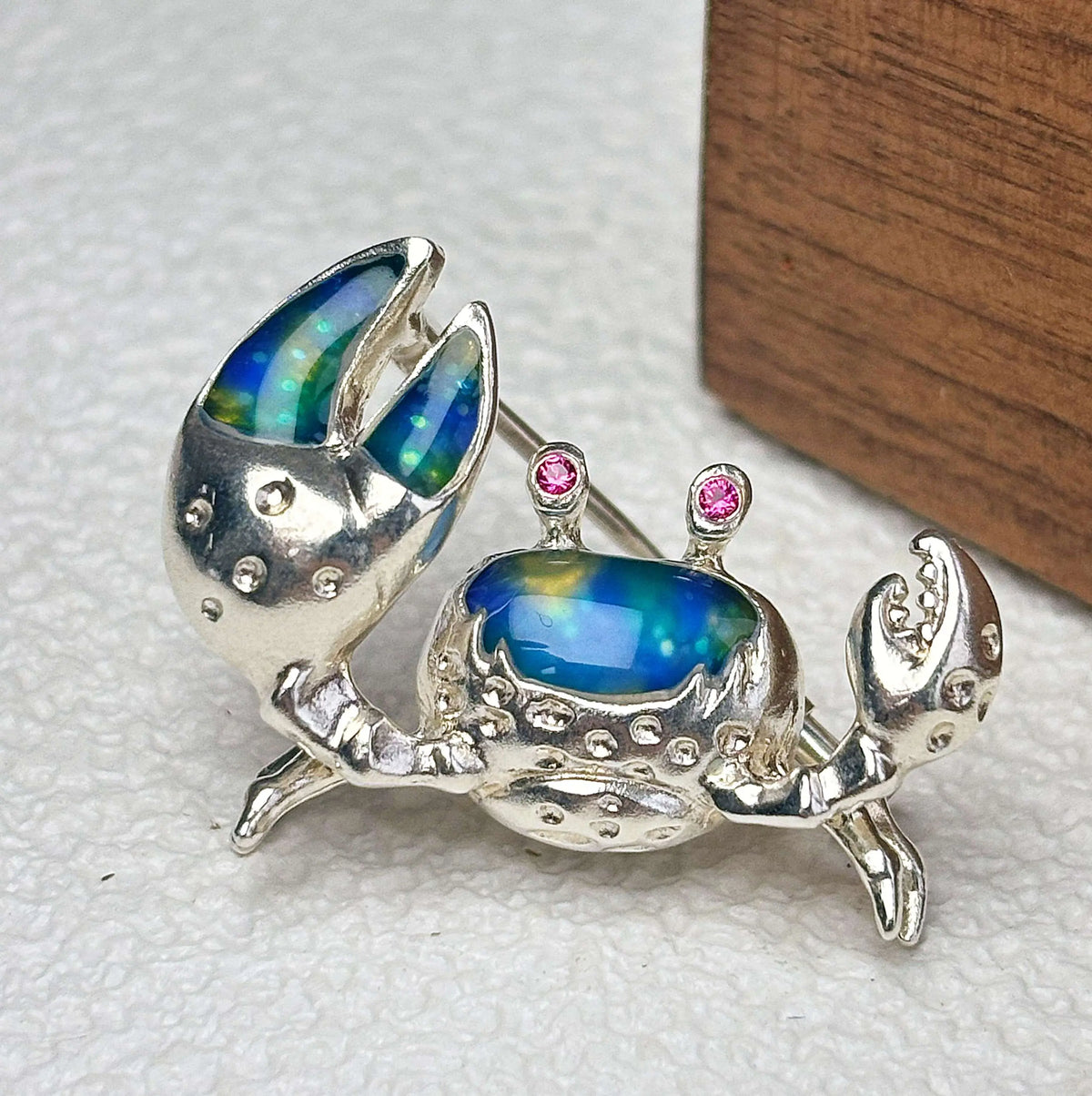 iridescent blue-green enamel shore crab silver brooch detail — jewelry close-up photo