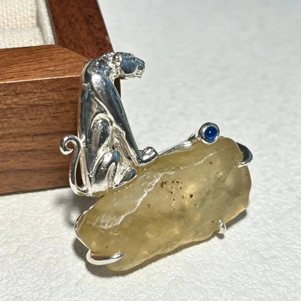 Sterling silver curled leopard brooch pinned to textile — handmade jewelry detail