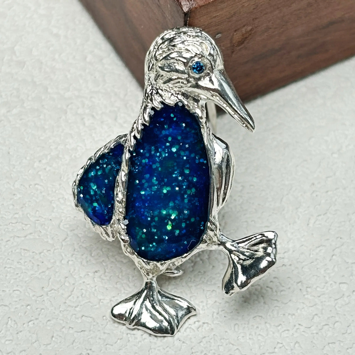 starry blue enamel waddling penguin silver brooch detail — jewelry close-up photo