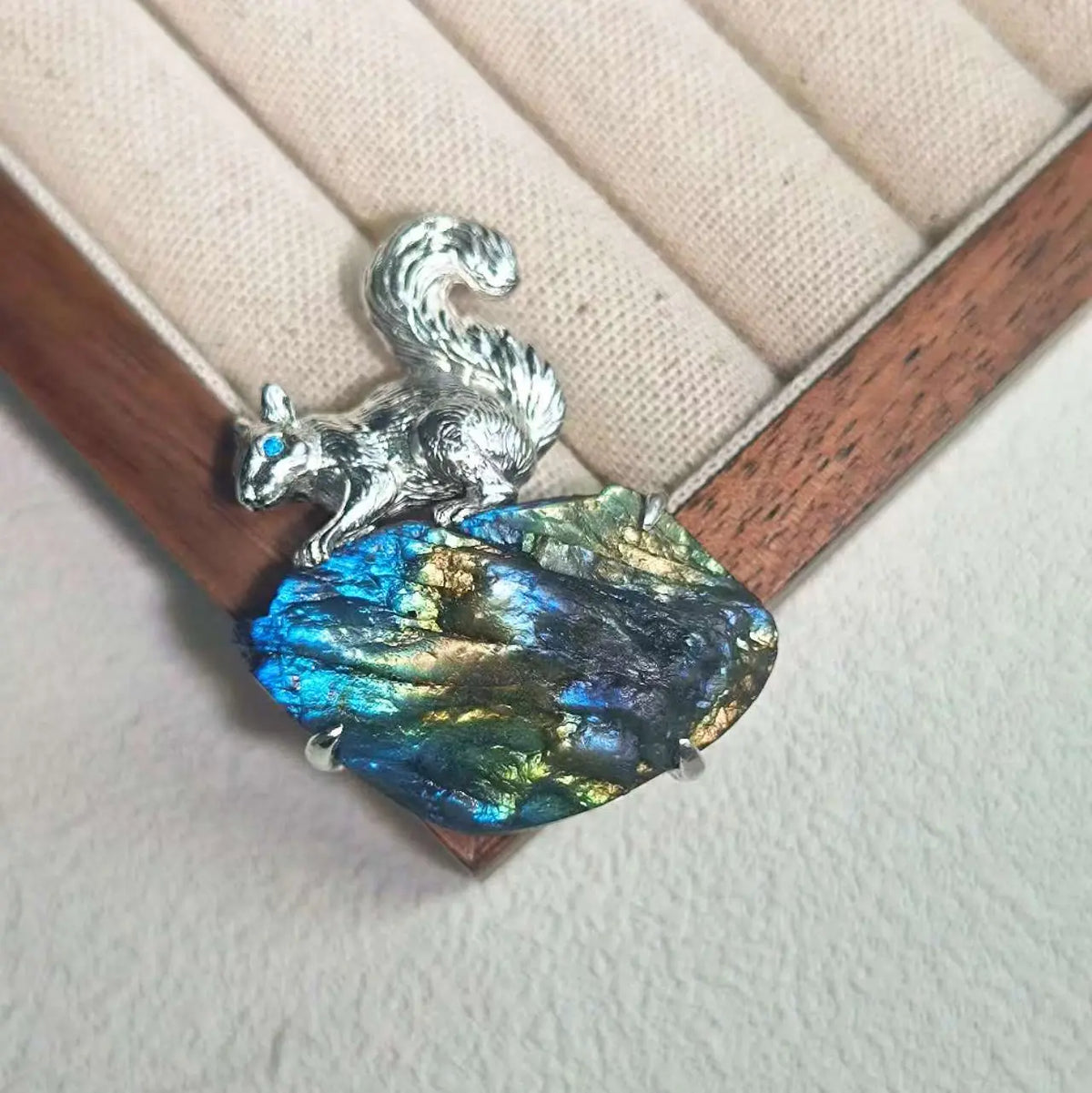 Sterling silver foraging squirrel brooch pinned to textile — handmade jewelry detail