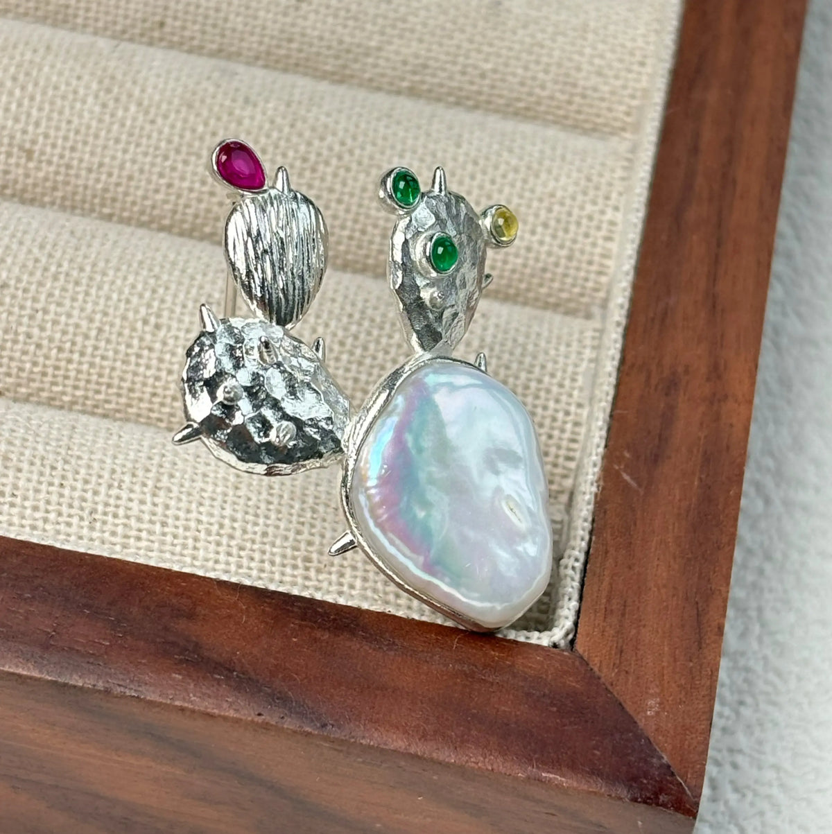 Sterling silver blooming cactus brooch pinned to textile — handmade jewelry detail