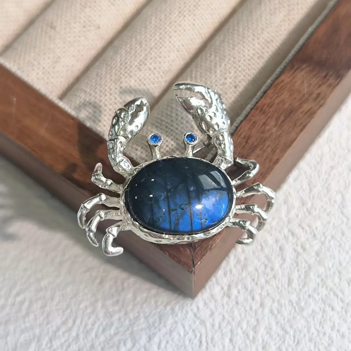 Sterling silver ocean crab brooch pinned to textile — handmade jewelry detail