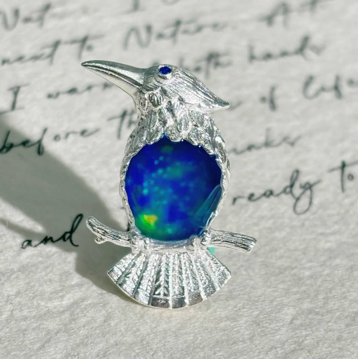 cobalt blue enamel perched kingfisher silver brooch detail — jewelry close-up photo