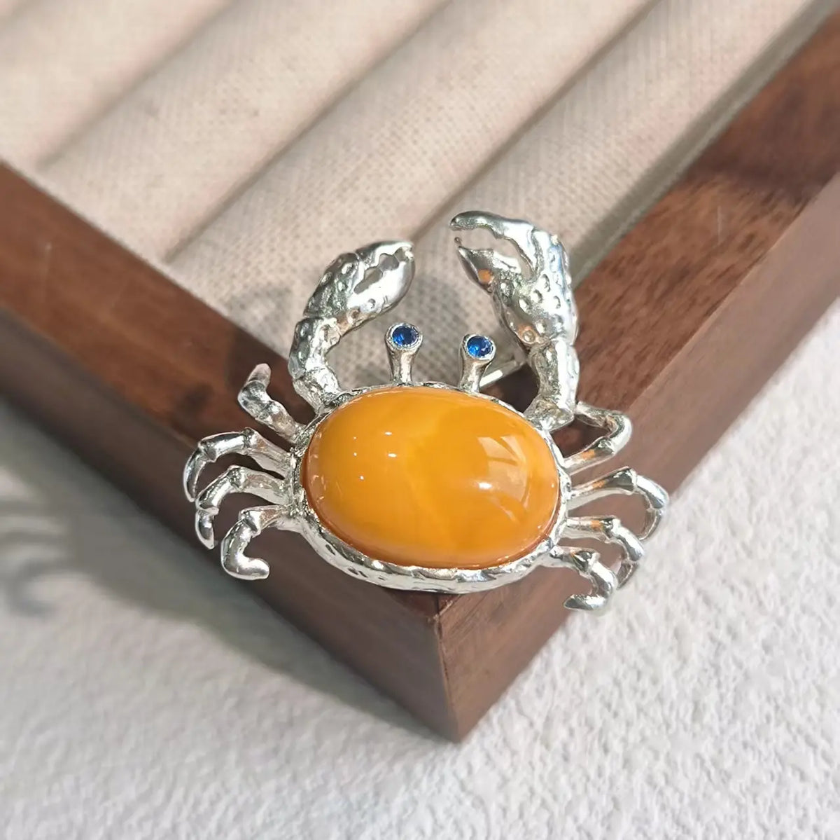 Sterling silver raised-claw crab brooch pinned to textile — handmade jewelry detail